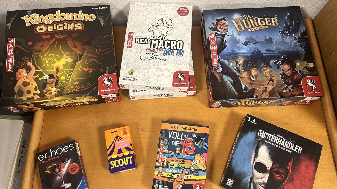 Verschiedene Brettspiele auf einem Tisch, darunter Kingdomino Origins und Micro Macro All In.