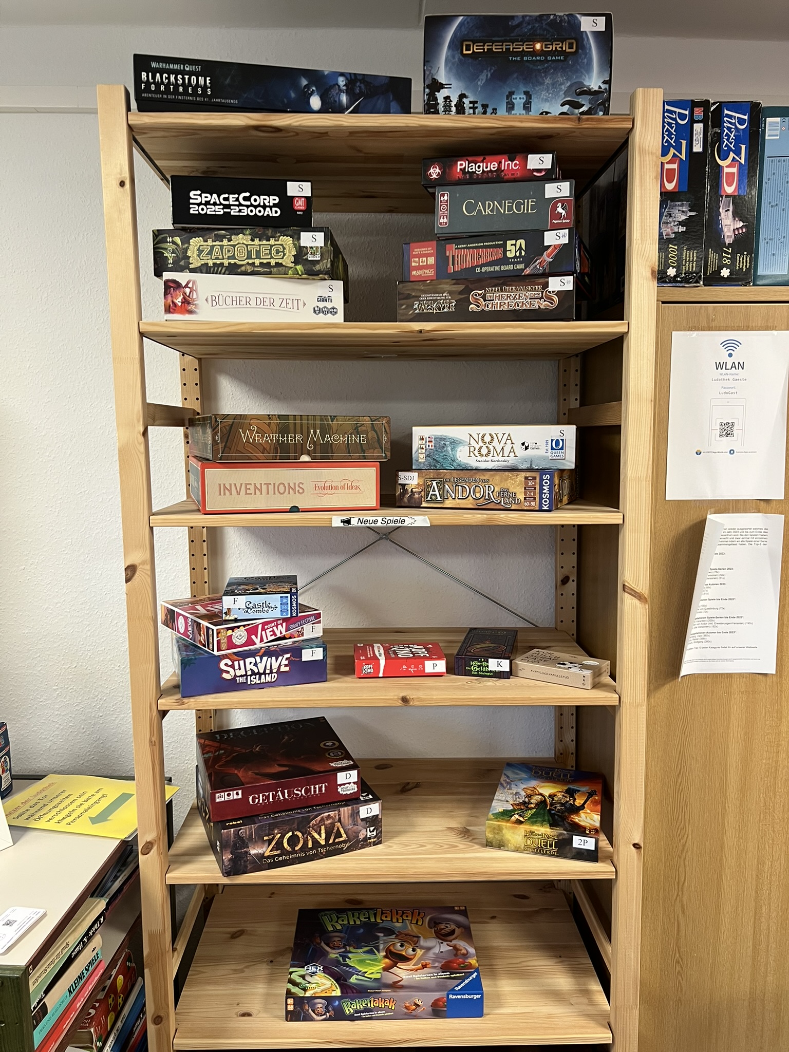 Holzregal mit verschiedenen Brettspielen, darunter Plague Inc. und Carnegie.