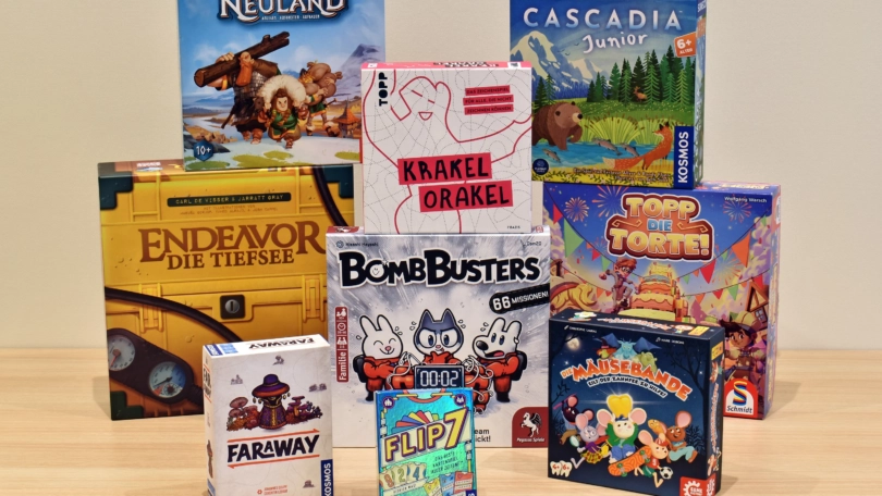 Verschiedene Brettspielverpackungen, darunter Neuland, Faraway und BombBusters, auf einem Tisch angeordnet.
