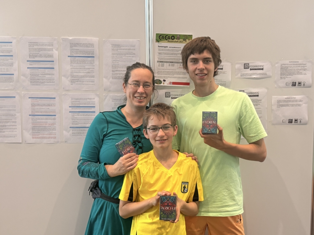 Eine Familie hält Brettspiele in den Händen, bestehend aus einer Frau und zwei Jungen.
