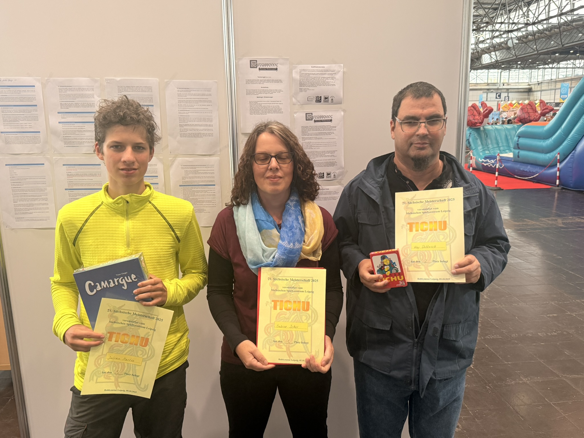 Drei Personen halten Spielpreise und Spiele in einer Indoor-Umgebung.