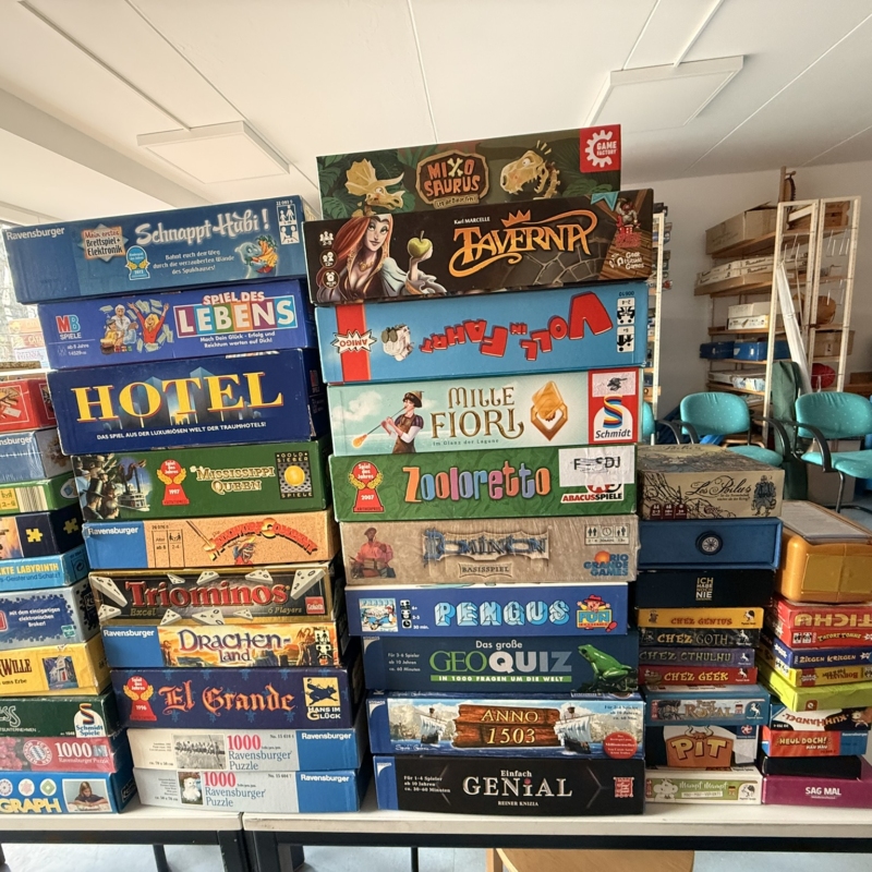 Stapel von Brettspielen in verschiedenen Boxen, darunter 'Mille Fiori', 'Zooloretto' und 'Hotel'.