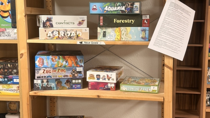 Regal mit verschiedenen Brettspielen, darunter Splendor, 7 Wonders und Zug um Zug, in einem Spielezentrum.