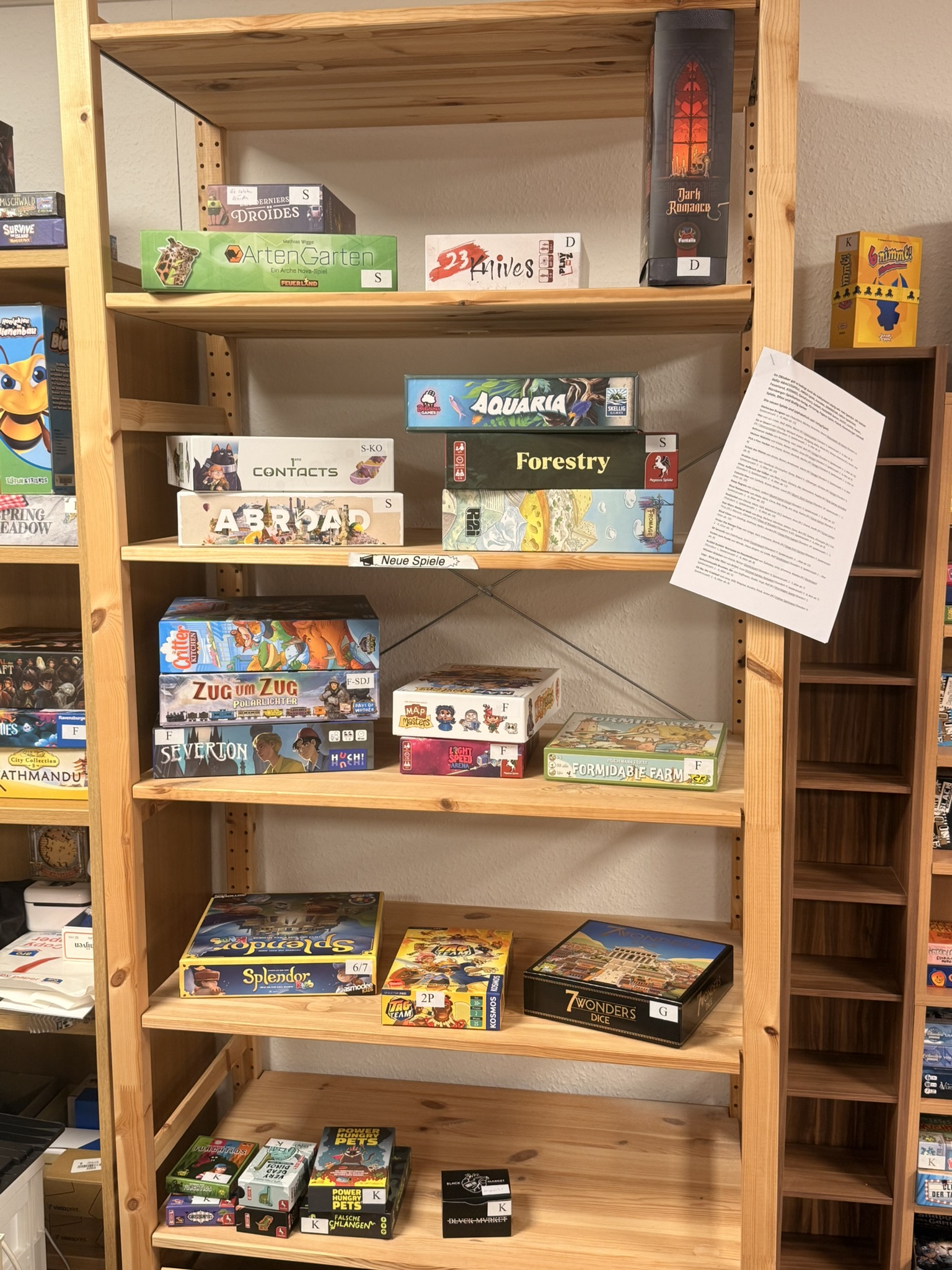 Regal mit verschiedenen Brettspielen, darunter Splendor, 7 Wonders und Zug um Zug, in einem Spielezentrum.