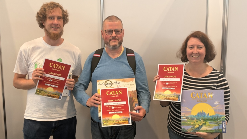 Bei der 26. Sächsischen Meisterschaft in Catan halten Jochen Hartmann, Marcel Schuchmann und Emöke Duro ihre Urkunden und Preise.