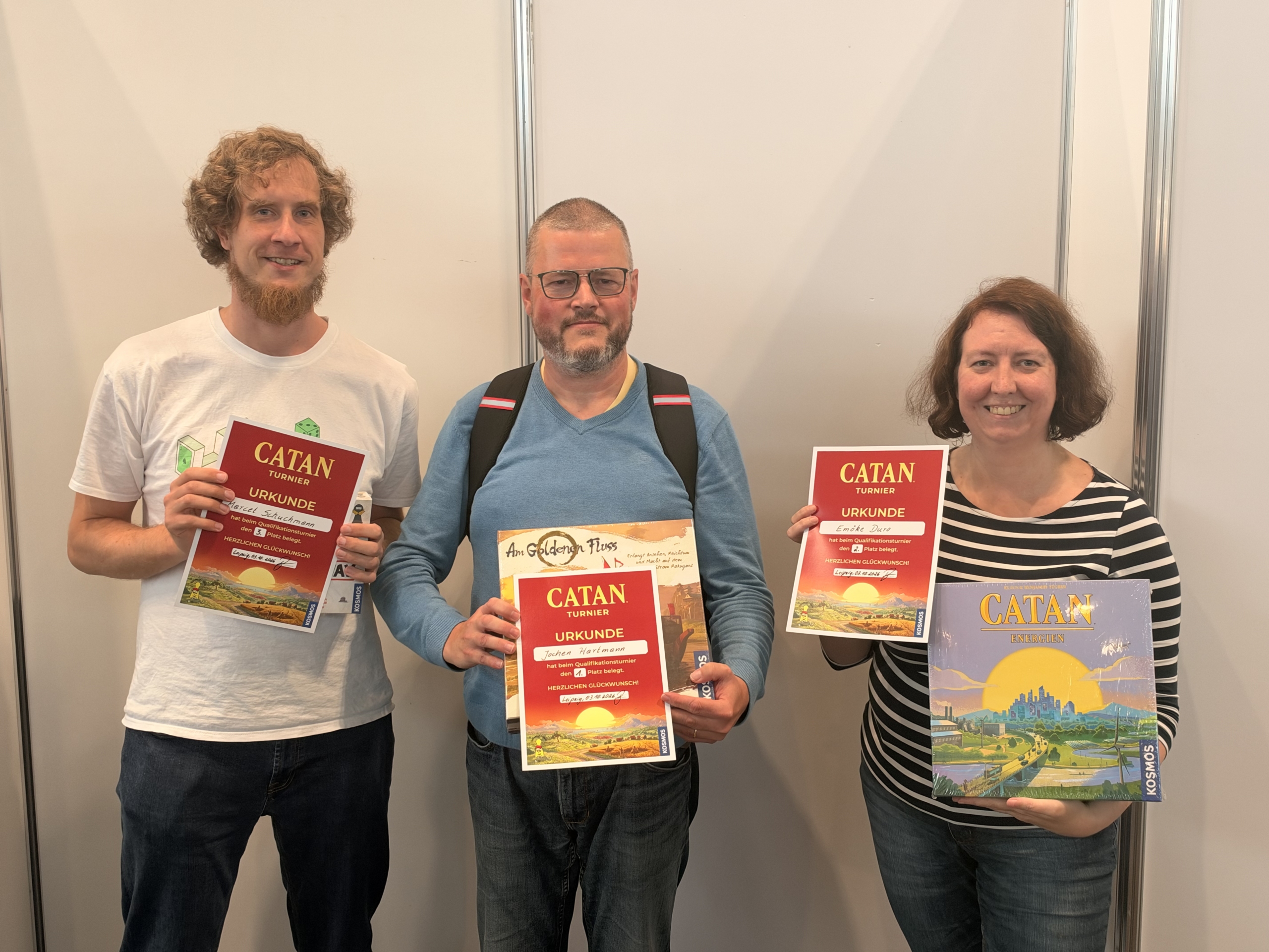 Bei der 26. Sächsischen Meisterschaft in Catan halten Jochen Hartmann, Marcel Schuchmann und Emöke Duro ihre Urkunden und Preise.